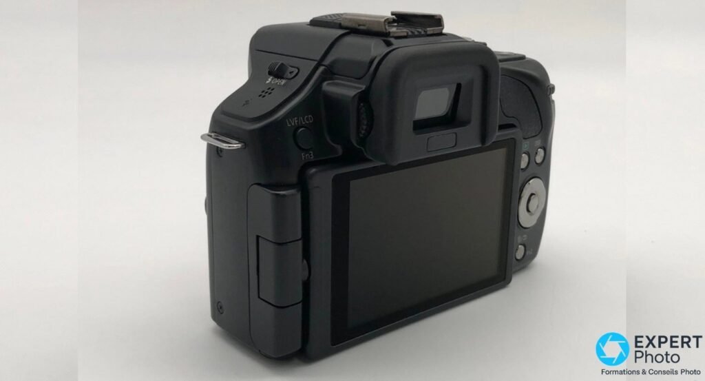 Vue arrière 3/4 gauche du Panasonic Lumix G5, levier OPEN du flash pop-up, bouton LVF/LCD Fn3 et viseur électronique.