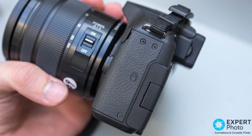 Panasonic Lumix G6 vu de profil côté droit tenu en main, switch ON/OFF POWER O.I.S de l'objectif visible