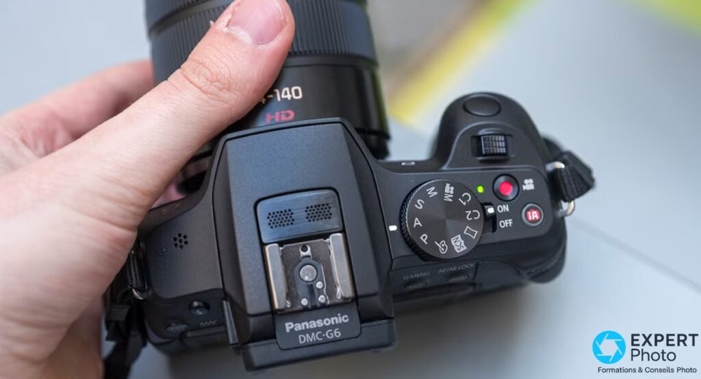 Vue de dessus du Panasonic Lumix G6 montrant l'étiquette Panasonic DMC-G6, la molette PASM et le bouton iA