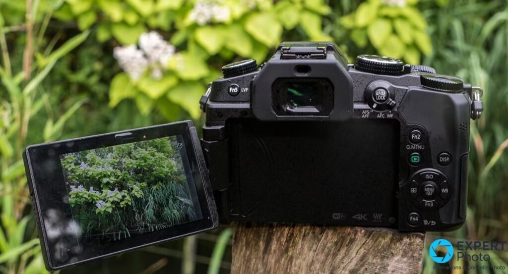 Panasonic Lumix G80 vu de dos sur souche bois, écran tactile orientable déplié à gauche, boutons Fn5 LVF visibles