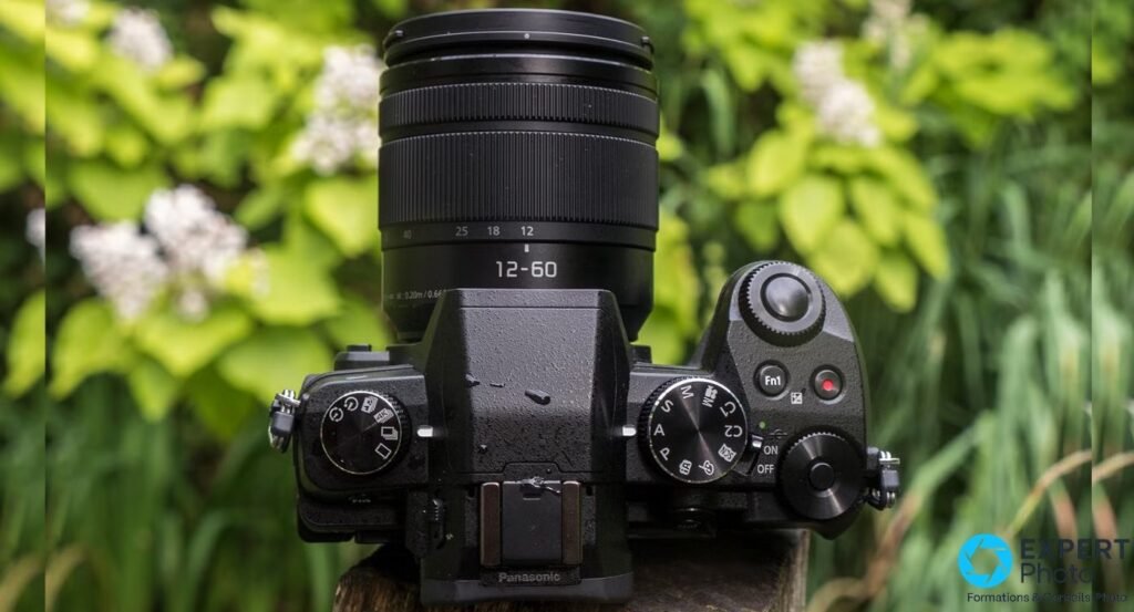 Panasonic Lumix G80 vu de dessus avec objectif Lumix 12-60 mm, molettes de modes visibles et logo Panasonic en bas 