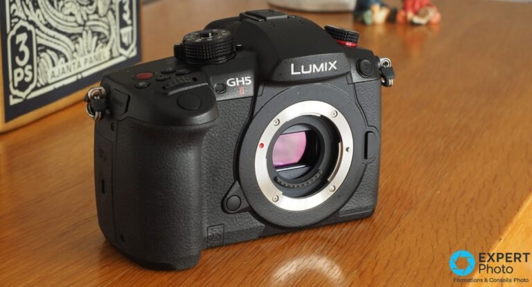 Panasonic Lumix GH5 II boîtier nu de face, monture Micro 4/3 exposée avec reflet violet, posé sur table en bois