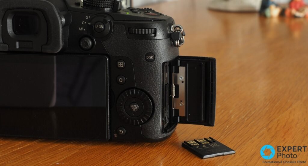 Panasonic GH5 II côté droit, trappe double slot SD ouverte et carte mémoire posée sur la table devant le boîtier 