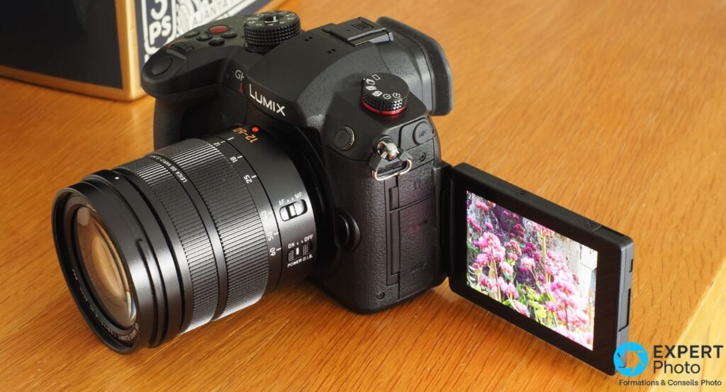  Panasonic GH5 II avec Leica 12-60 mm monté, écran orientable déplié sur le côté droit affichant image de fleurs roses