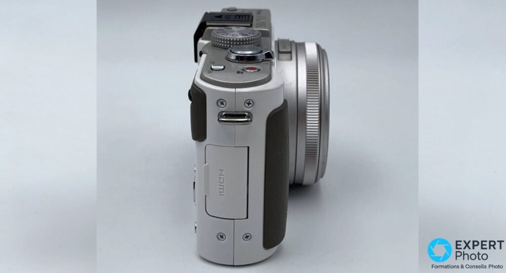 Panasonic LX7 blanc de profil droit, trappe HDMI gravée visible, objectif rétracté.