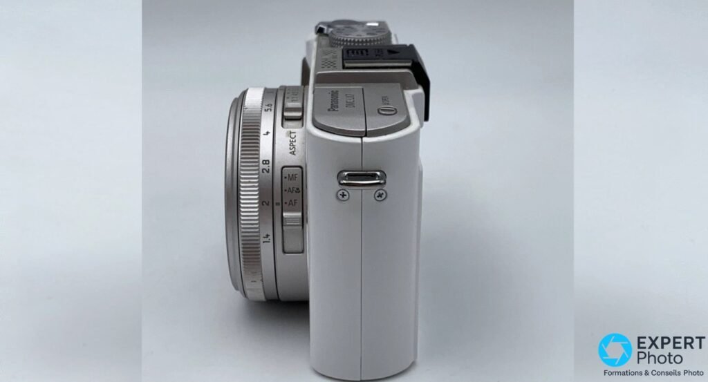 Panasonic LX7 de profil gauche, bague d'ouverture graduée f/1,4 à f/5,6 et sélecteur MF/AF visibles.