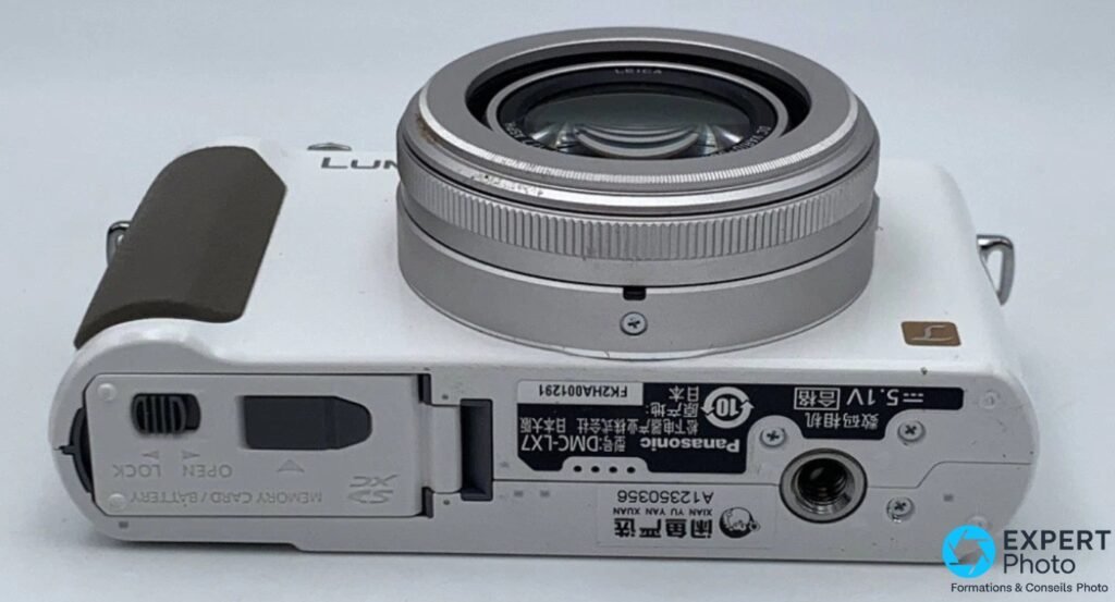 Vue de dessous du Panasonic LX7 blanc : trappe carte SD et batterie, filetage trépied 1/4".