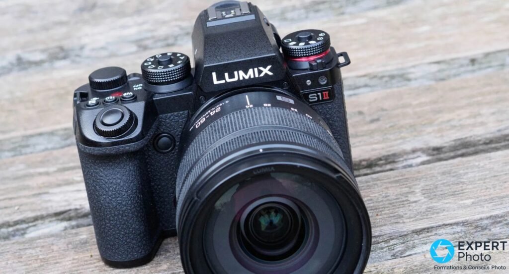 Panasonic Lumix S1 II noir, vue 3/4 avant plongée, zoom 24-60mm monté, marquage LUMIX S1II lisible, fond bois clair