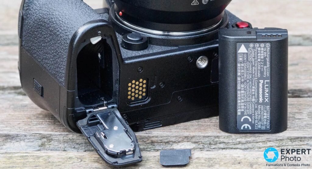 Panasonic Lumix S1 II compartiment batterie ouvert, batterie DMW-BLK22 3200 mAh extraite, connecteurs dorés visibles