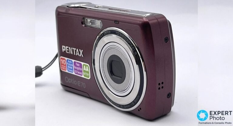 Compact numérique Pentax Optio E70 prune, vu en trois quarts avant, objectif rétracté, stickers 10 Mpx visibles.