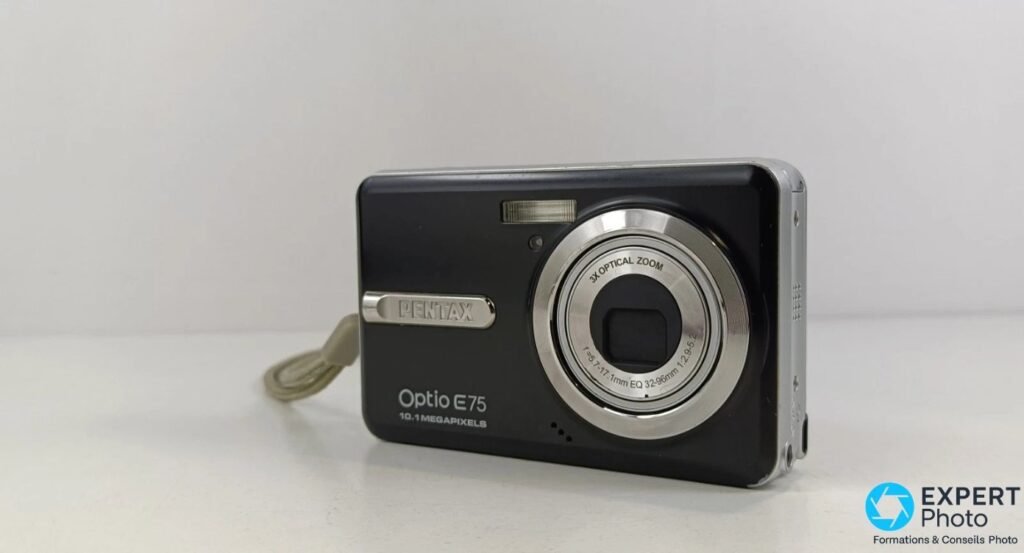 Pentax Optio E75 en vue trois quarts avant droite, objectif zoom 3x sorti, focale f=5,7-17,1 mm visible.