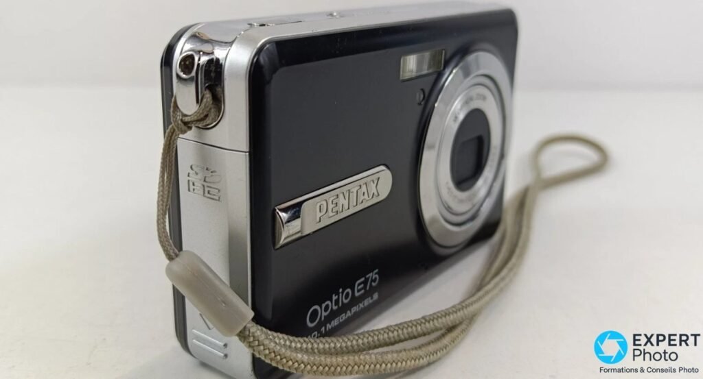 Pentax Optio E75 en vue trois quarts avant gauche, logo PENTAX, mention Optio E75 10.1 MEGAPIXELS et logo SD HC. 