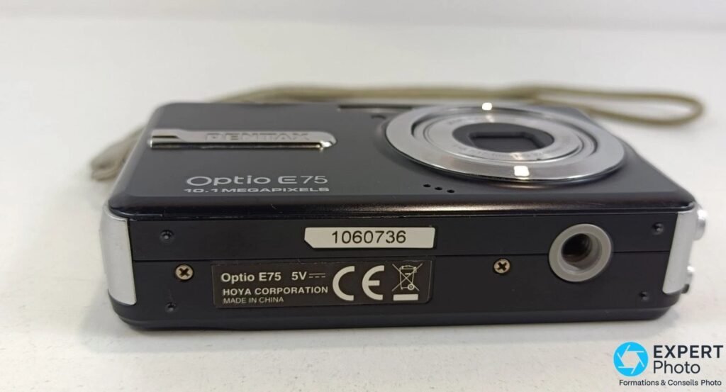 Dessous du Pentax Optio E75 avec étiquette série 1060736, mention Hoya Corporation, marquage CE et pas-de-vis trépied. 