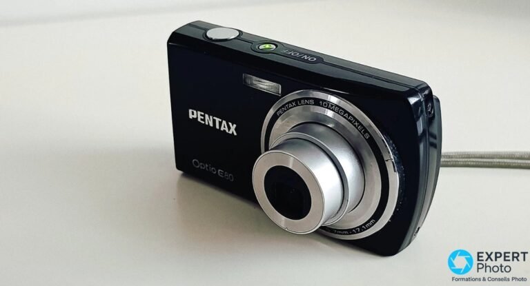 Pentax Optio E80 noir vu de trois quarts avant, objectif déployé et LED verte allumée à côté du déclencheur.