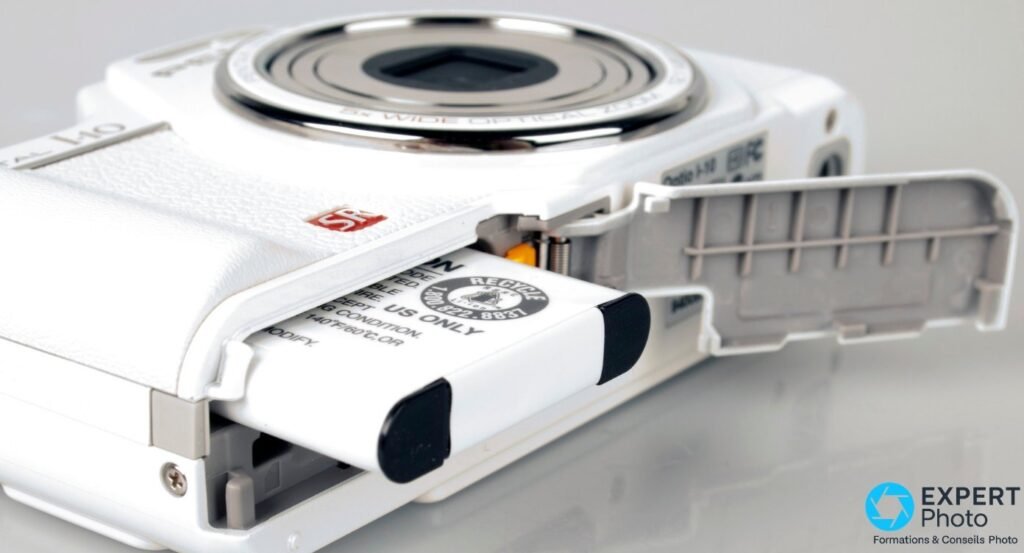 Compartiment batterie du Pentax Optio I-10 blanc ouvert, accumulateur partiellement extrait avec mention recyclage.