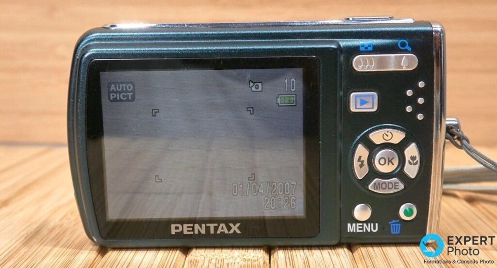 Vue arrière du Pentax Optio M40 avec écran LCD 2,5 pouces allumé et commandes MENU, OK, MODE, pavé directionnel.