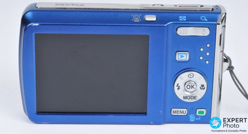 Pentax Optio M60 bleu, face arrière, écran LCD éteint, molette OK/MODE, boutons MENU et lecture visibles