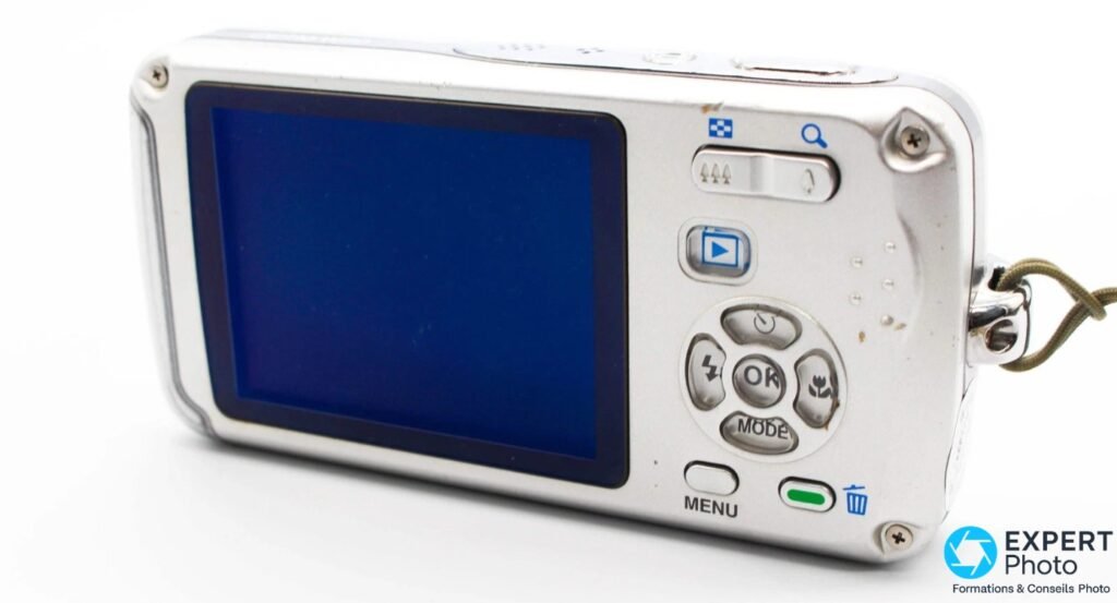 Pentax Optio W30, dos avec écran LCD bleu allumé, boutons OK, MODE, MENU et molette de navigation, fond blanc