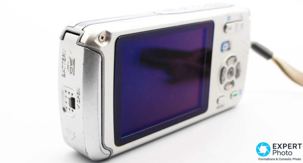 Pentax Optio W30, tranche gauche, trappe batterie et carte SD ouverte, inscriptions BATTERY, SD et OPEN visibles