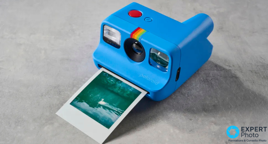 Polaroid Go Gen 2 bleu sur béton avec tirage carré blanc partiellement sorti de la fente, image d'un cygne visible