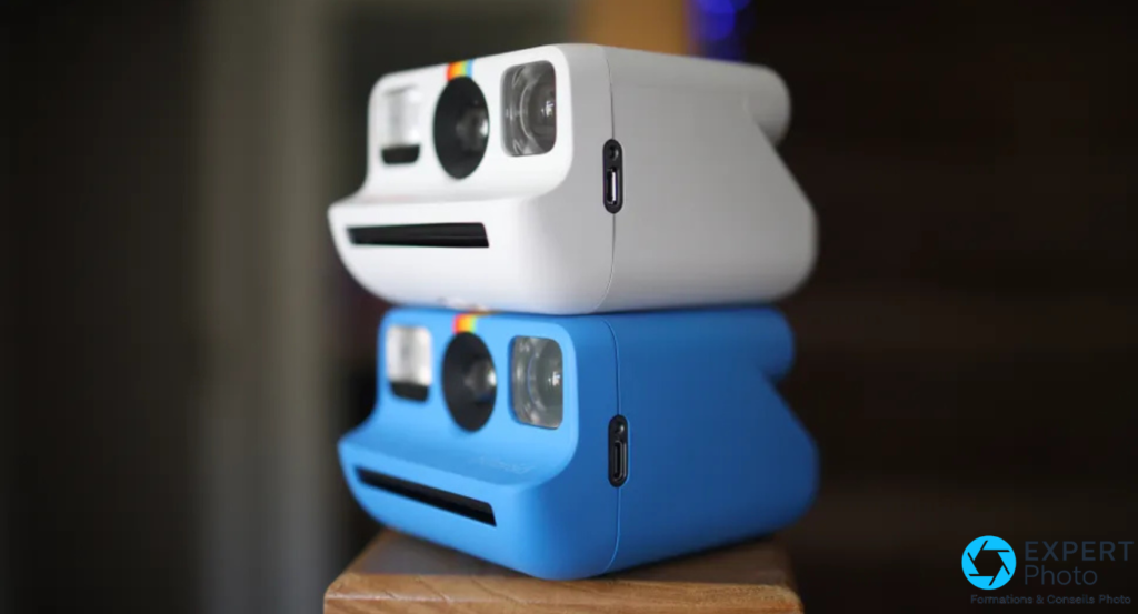 Deux appareils Polaroid Go empilés, coloris blanc dessus et bleu dessous, sur surface en bois
