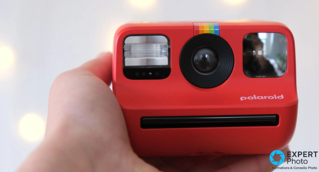 Polaroid Go Gen 2 rouge tenu en main, face avant montrant flash, objectif central et miroir selfie rectangulaire