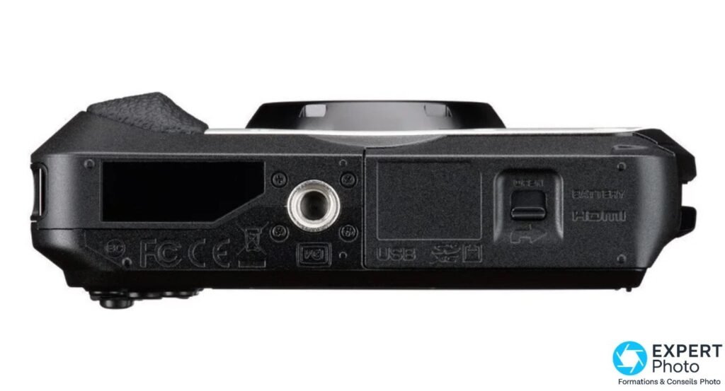 Dessous du Ricoh G900 II : filetage de trépied, trappe fermée avec mentions BATTERY, HDMI, USB et logos FCC, CE.