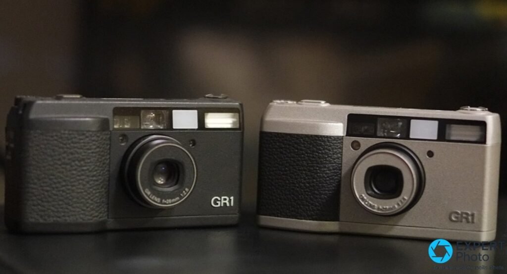 Deux Ricoh GR1 argentiques en finitions noire et gris champagne, vus de face, marquage GR1 lisible sur les deux.