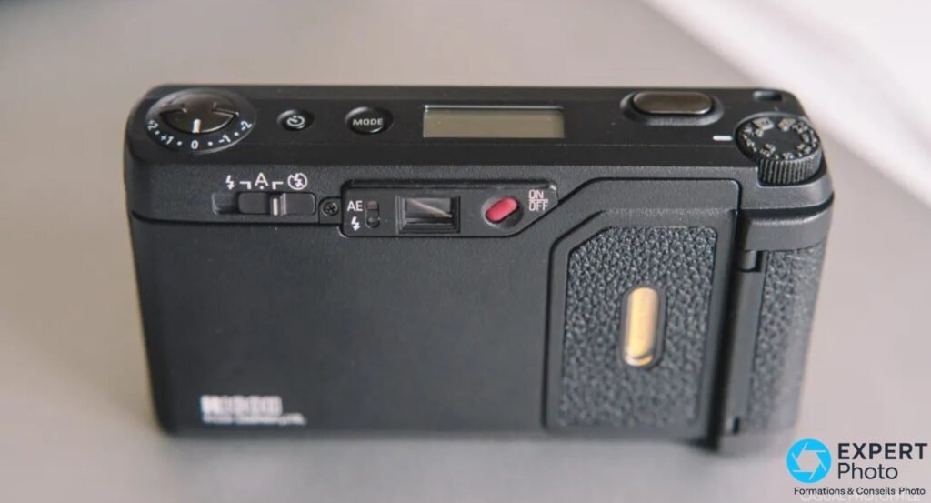  Vue arriere du Ricoh GR1v noir : ecran LCD superieur, selecteur de flash A/auto, AE switch et bouton ON/OFF rouge.