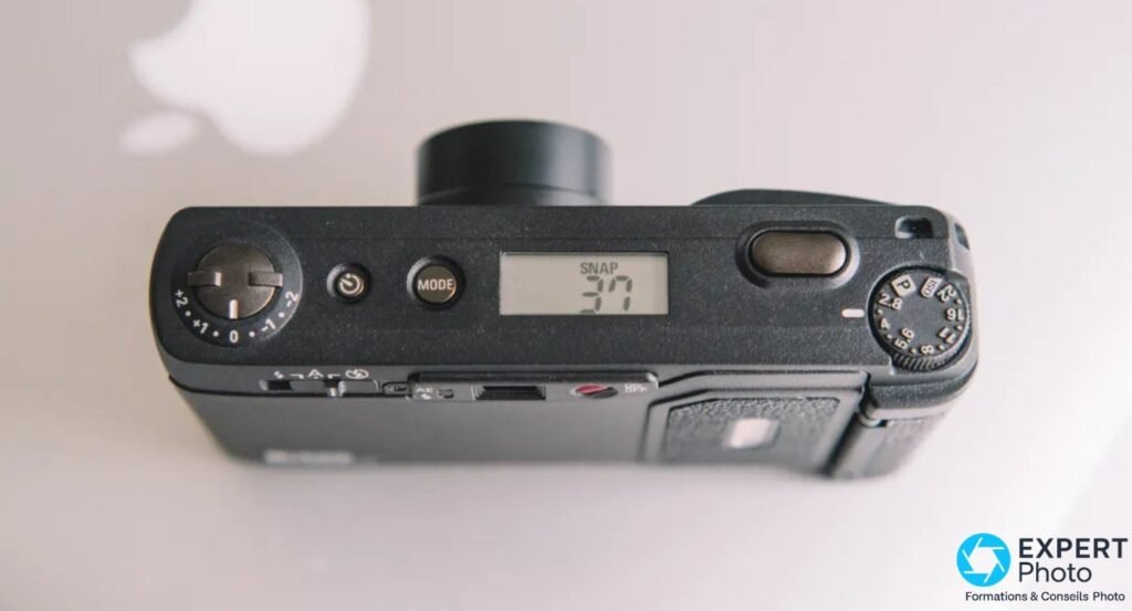Ricoh GR1v vu de dessus, ecran LCD affichant le mode SNAP et la valeur 37, objectif sorti pret au declenchement. 