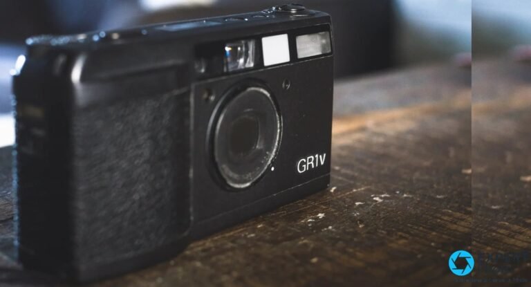Compact argentique Ricoh GR1v noir vu en trois quarts avant sur une table en bois, marquage GR1v lisible a droite.