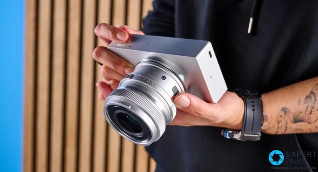 Sigma BF argenté tenu à deux mains, objectif argenté focale fixe monté, fond bleu et lames bois