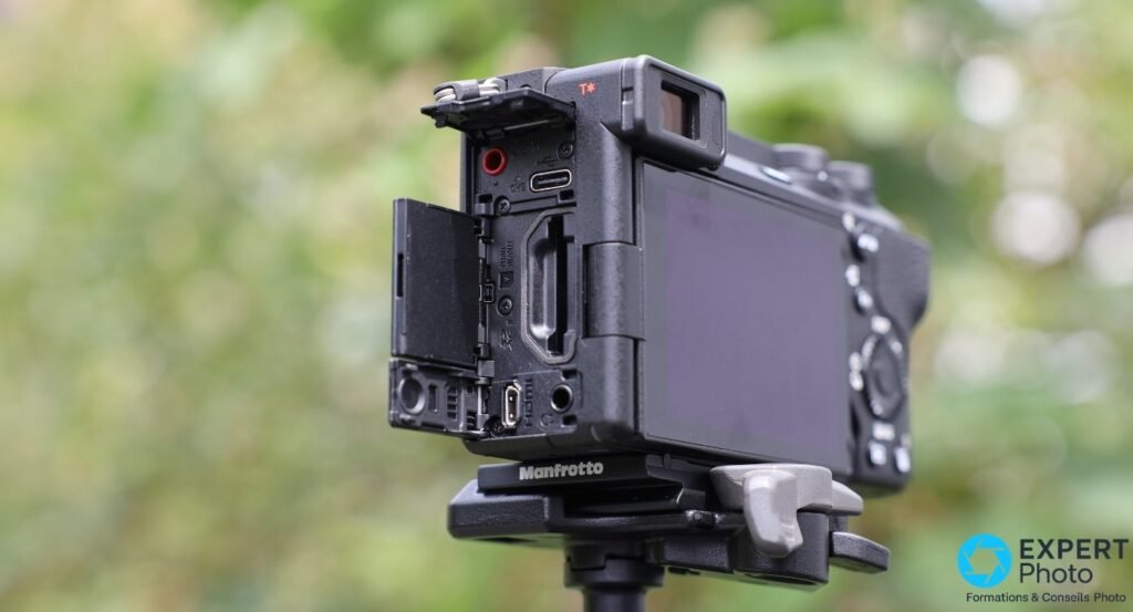 Sony A6700 sur trépied Manfrotto, trappe latérale ouverte montrant entrée micro rouge, USB-C et port HDMI.