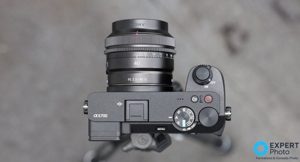 Sony A6700 vu de dessus avec FE 2.5/40 G monté, dial PASM, bouton REC vidéo, MENU et α6700 lisibles.