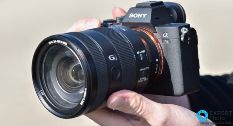 Test Sony Alpha 7 III : reportage, mariage et portrait avant la vidéo Sony A7 III avec objectif FE 24-105 G OSS, tenu en main, vue 3/4 avant gauche sur fond beige flou