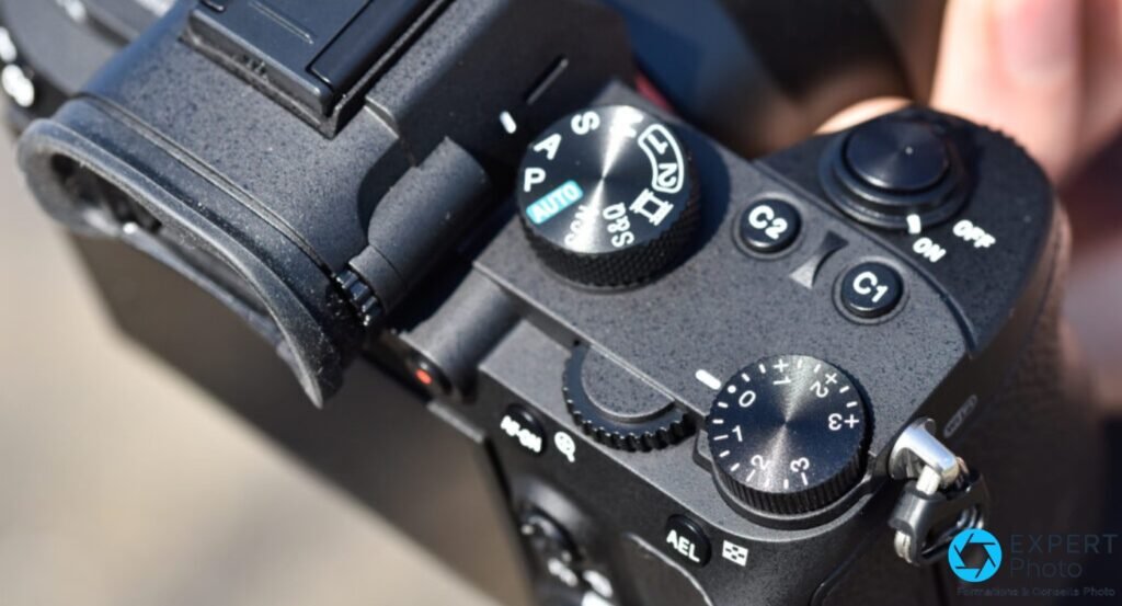 Dessus du Sony A7 III en plongée : molette de modes avec positions AUTO, P, A, S, M, boutons C1, C2 et roue de correction d'exposition lisibles