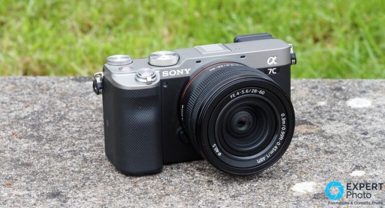 Sony A7C : test terrain, avis honnête et faut-il encore l’acheter en 2026 ? Sony A7C argent et noir équipé du Sony FE 28-60 mm posé sur une dalle de pierre, fond herbe verte.