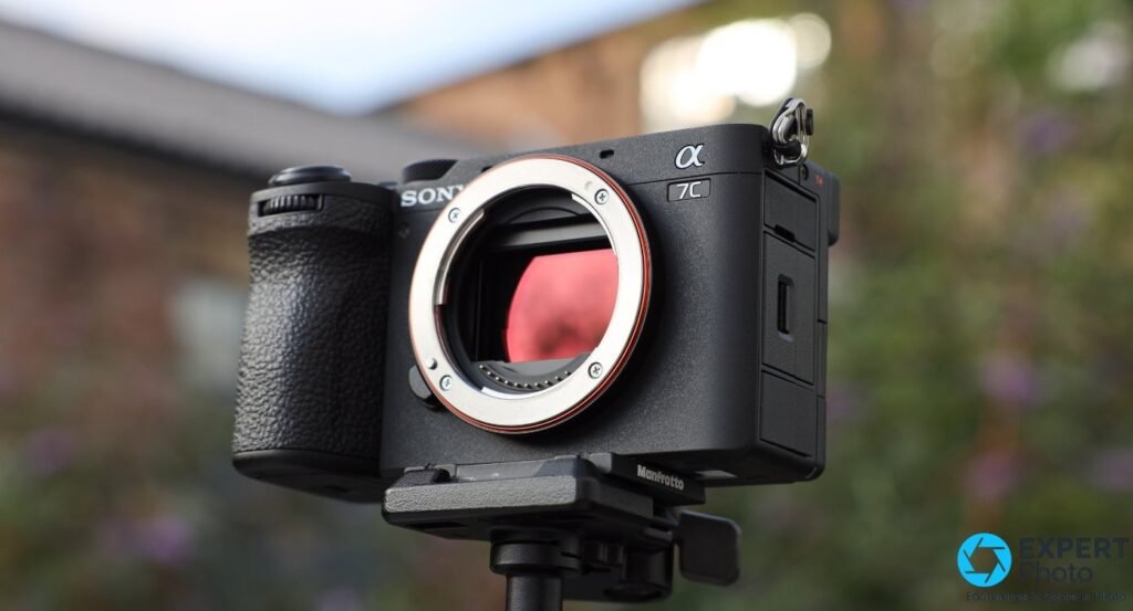 Sony A7C II boîtier nu vu de face, monté sur trépied Manfrotto, monture E ouverte, jardin en arrière-plan flou