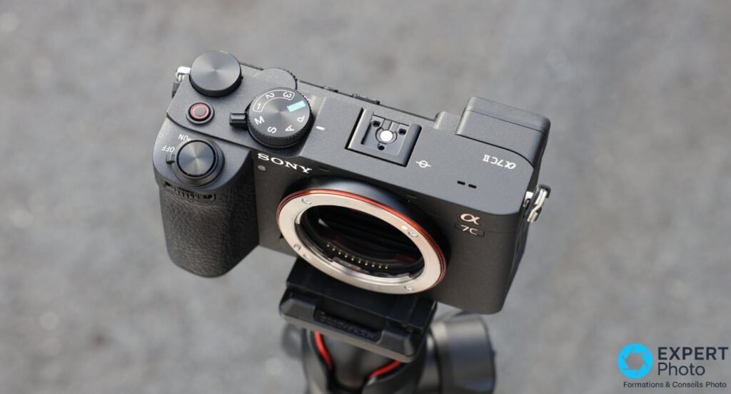 Sony A7C II boîtier nu vu de dessus, molette de mode sur AUTO, déclencheur et roue avant visibles, sur trépied