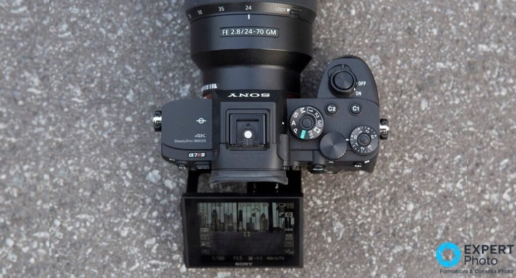 Sony A7R IV vu du dessus avec écran orientable affichant un live view de skyline, objectif FE 24-70 GM monté