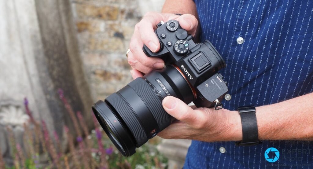 Sony A7R IV tenu à deux mains, équipé d'un objectif Sony FE 16-35 mm f/2.8 GM, en extérieur