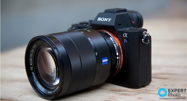 Sony A7S II noir équipé d'un Zeiss Vario-Tessar FE 4/24-70 ZA OSS, vue 3/4 avant sur table en bois clair.