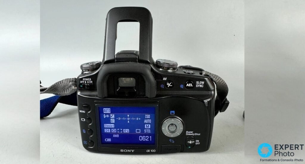Vue arrière du Sony Alpha 100 avec écran LCD allumé affichant mode AUTO, ISO, balance des blancs et compteur de prises.