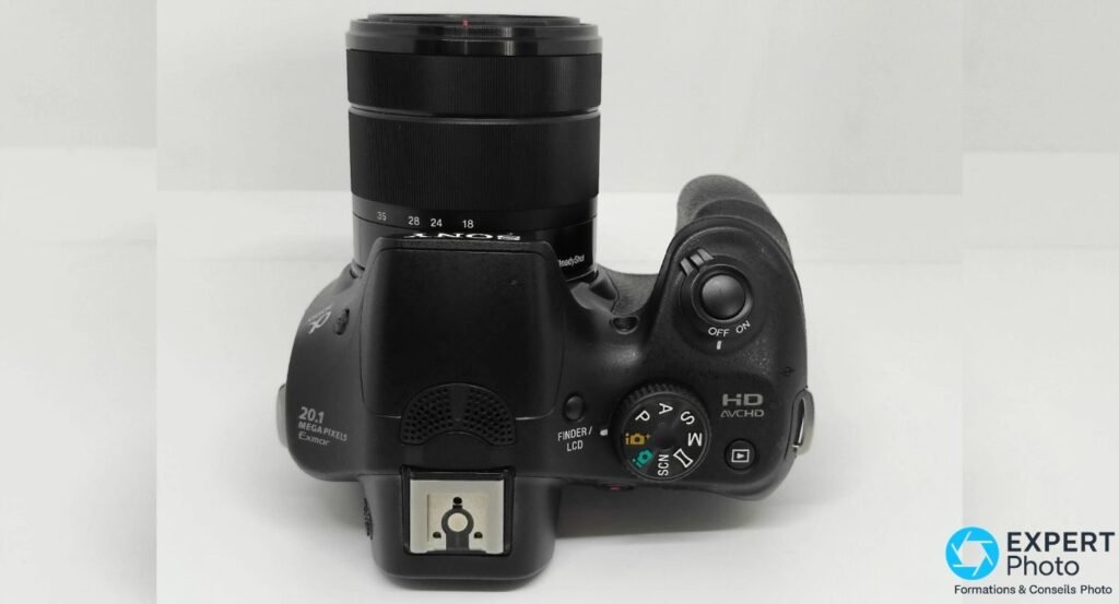 Vue de dessus du Sony Alpha 3000 avec molette des modes P/A/S/M/SCN, déclencheur, griffe flash et marquage HD AVCHD. 