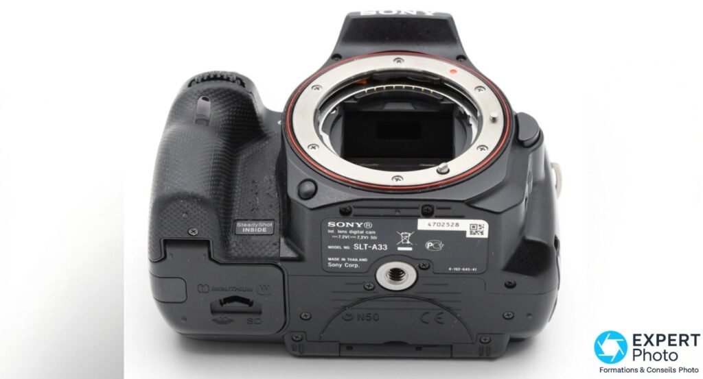 Semelle du Sony SLT-A33 avec étiquette modèle SLT-A33, SteadyShot INSIDE, compartiment batterie INFOLITHIUM et SD 
