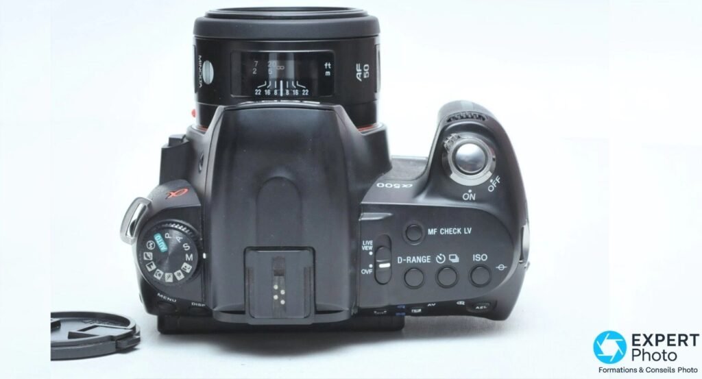 Vue de dessus du Sony Alpha 500 avec molette des modes, sélecteur Live View/OVF et objectif Minolta monté.