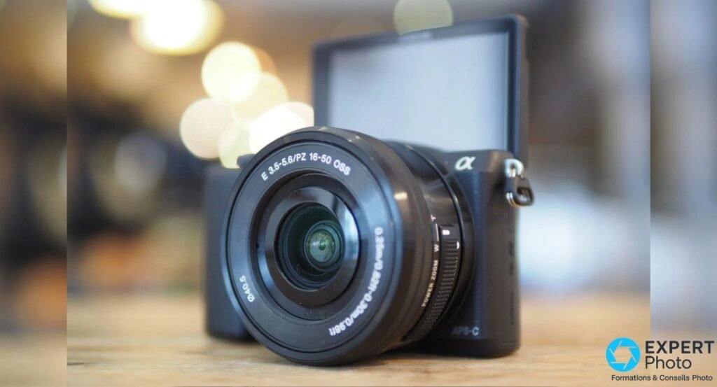 Sony Alpha 5100 équipé du zoom 16-50 mm OSS, écran tactile rabattu à 180 degrés vers le haut en position selfie.