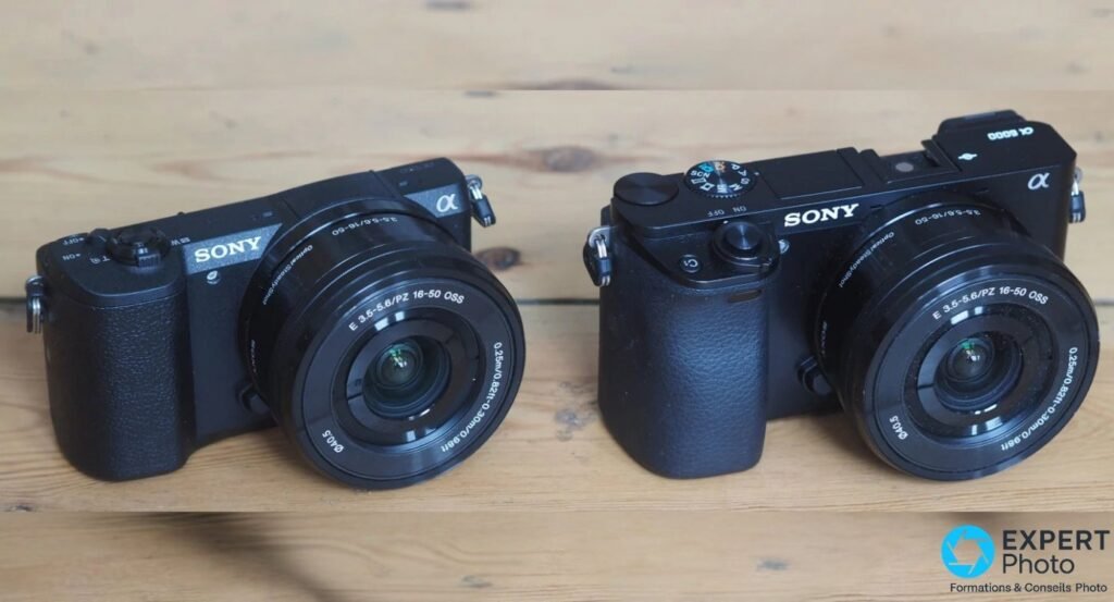 Sony Alpha 5100 et A6000 côte à côte sur planches de bois, équipés du même zoom Sony E 16-50 mm OSS, vue 3/4 avant.
