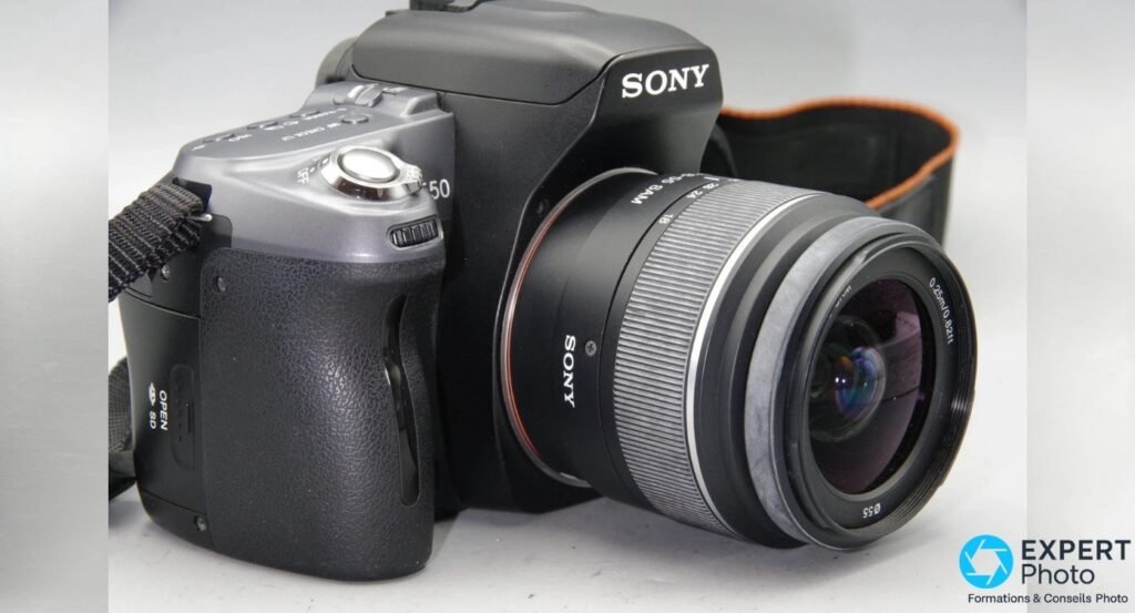Reflex Sony Alpha 550 en trois-quarts avant droite, côté grip, objectif Sony DT 18-55 SAM déployé en zoom.