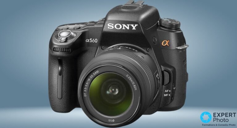 Reflex Sony Alpha 560 noir vu de trois-quarts avant gauche avec optique kit DT 18-55 SAM montée, fond bleu-gris.